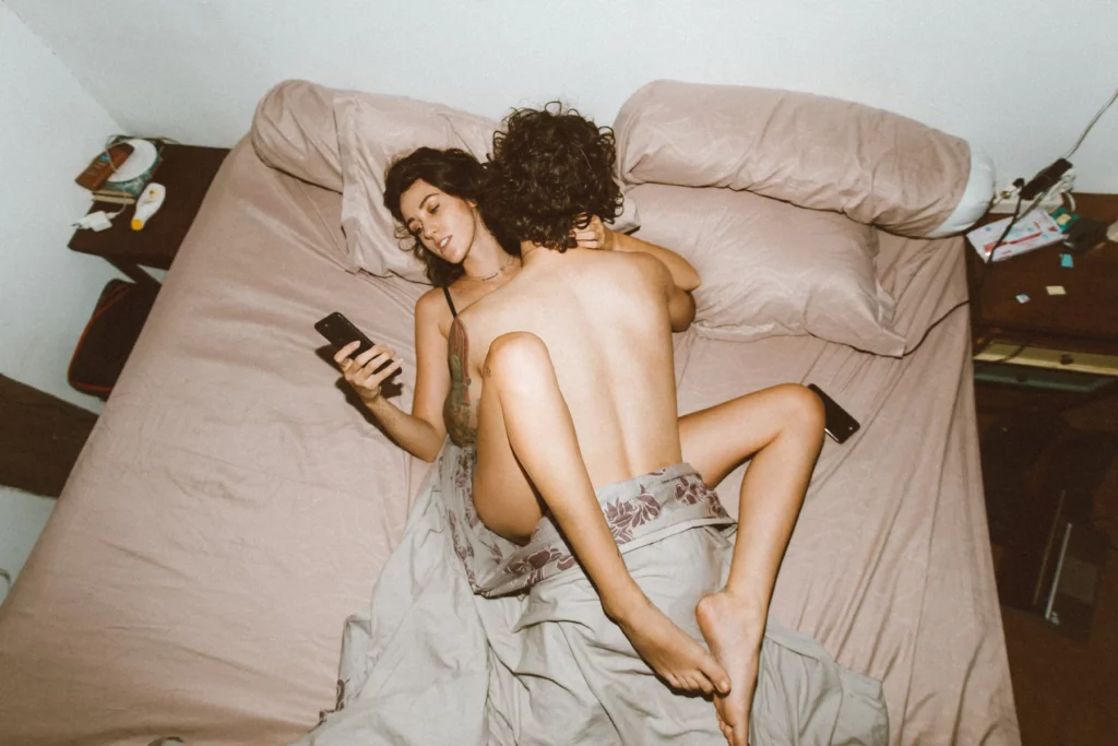 A couple having sex while looking at a smartphone