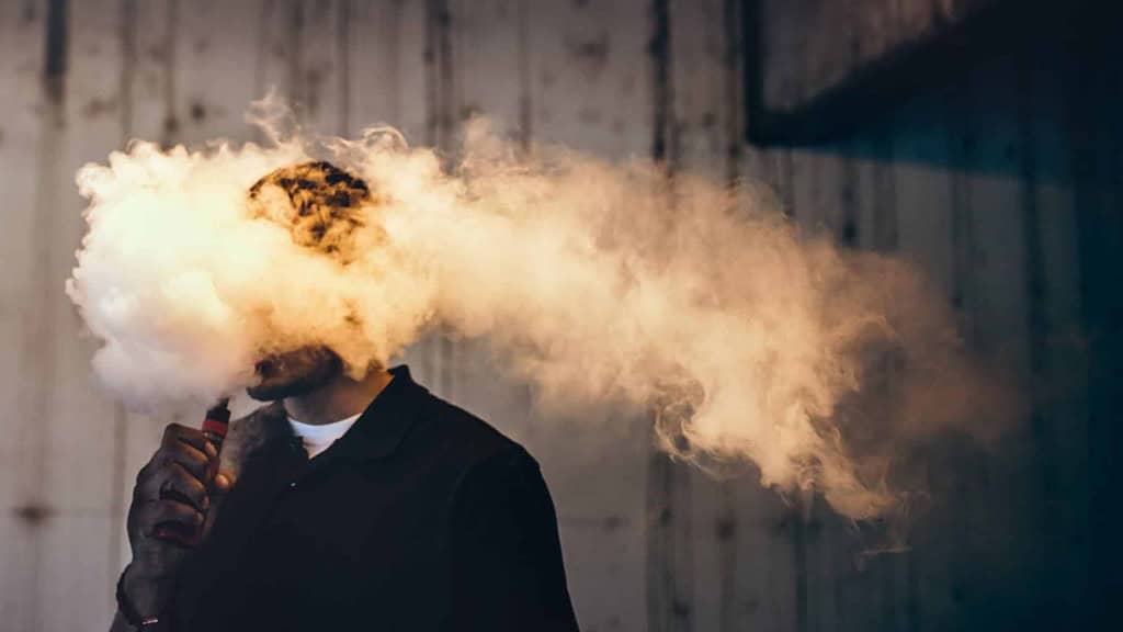 Man exhaling thick vape clouds.